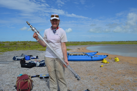 A woman standing by the lakeshore doing research